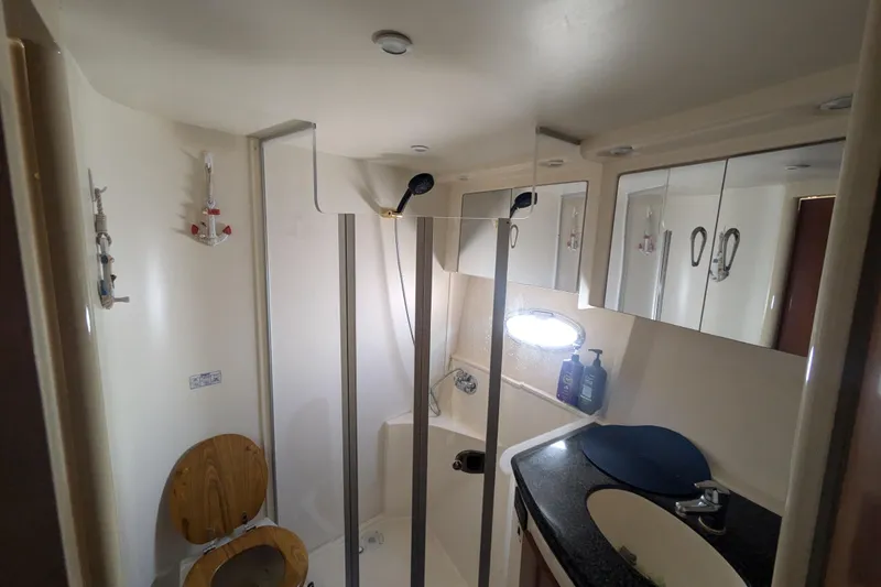 Slide: The Image of Bathroom interior of 2004 Carver 360 Mariner yacht, featuring shower, sink, and wooden toilet seat. - 21