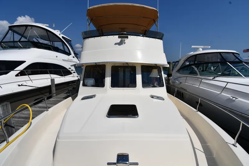 Slide: The Image of 2006 Mainship 40 Trawler docked between two yachts under a clear blue sky. - 10