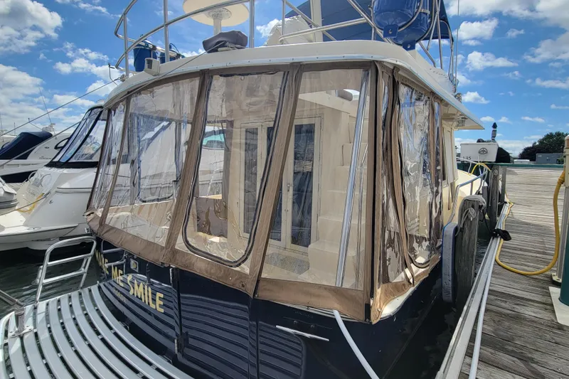 Slide: The Image of 2006 Mainship 40 Trawler docked, featuring enclosed deck and clear weather panels. - 103