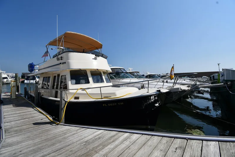 Slide: The Image of 2006 Mainship 40 Trawler docked at marina under clear blue sky. - 2