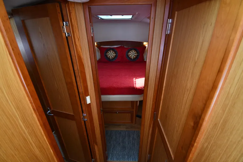 Slide: The Image of 2006 Mainship 40 Trawler cabin interior with wooden doors and red bedding. - 38