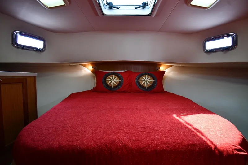 Slide: The Image of Cozy cabin interior of 2006 Mainship 40 Trawler with red bedding and nautical decor. - 39