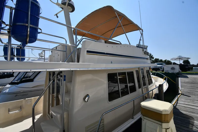 Slide: The Image of 2006 Mainship 40 Trawler docked, featuring upper deck and canopy in marina setting. - 5