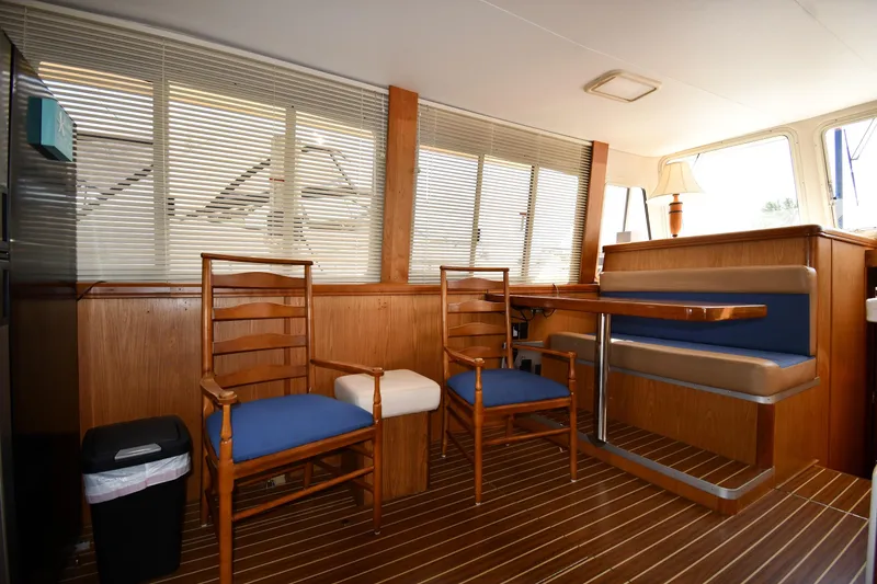 Slide: The Image of 2006 Mainship 40 Trawler interior with wooden dining area and blue cushioned seating. - 61