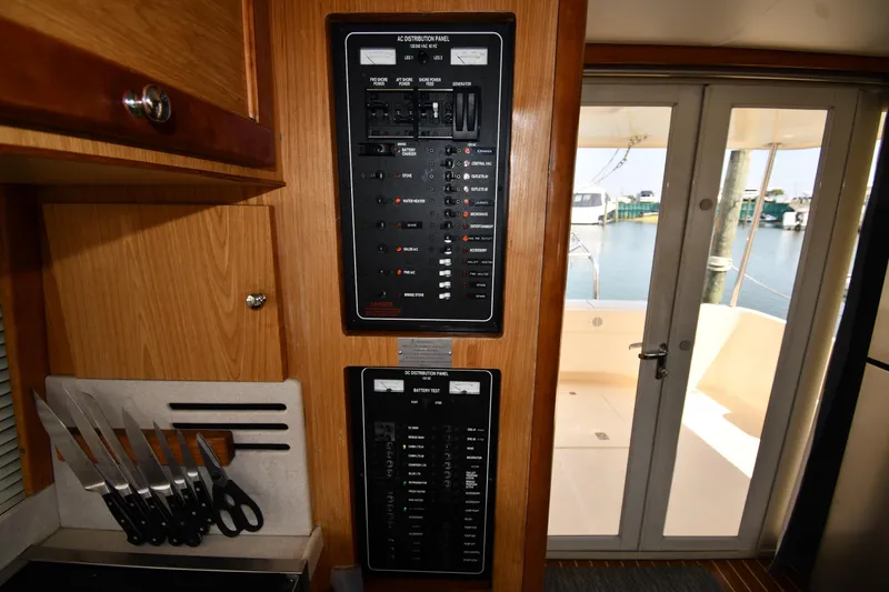 Slide: The Image of Electrical panel and knife set inside 2006 Mainship 40 Trawler, with view of deck and water. - 66