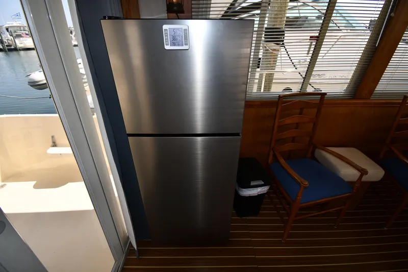 Slide: The Image of Interior of 2006 Mainship 40 Trawler with stainless steel refrigerator and wooden chairs. - 67