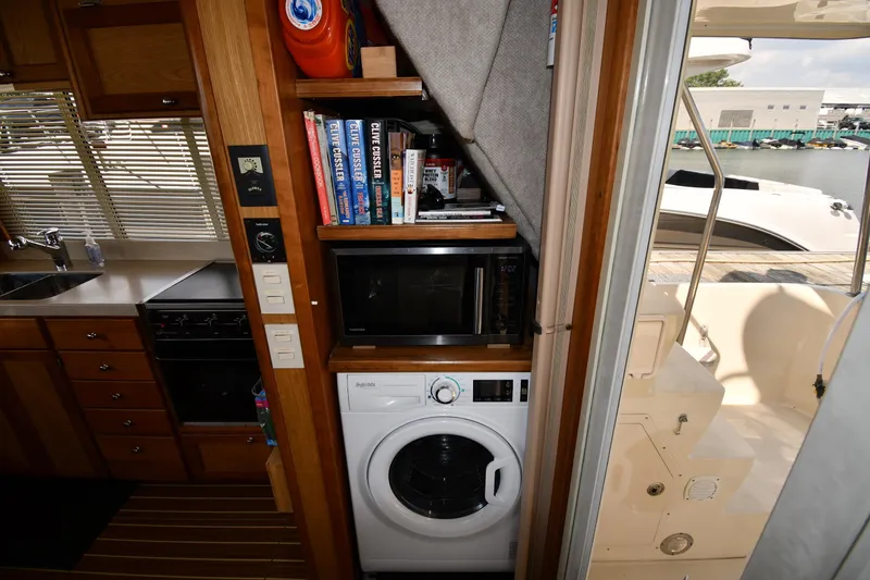 Slide: The Image of 2006 Mainship 40 Trawler interior with kitchen, washer, and books. - 68