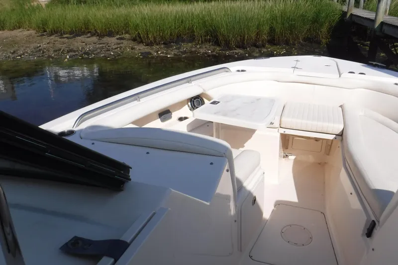 Slide: The Image of 2016 Grady White 355 Freedom boat interior with seating and table, near grassy shoreline. - 7