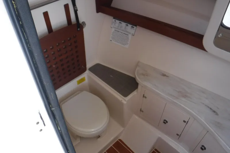 Slide: The Image of 2016 Grady White 355 Freedom boat bathroom interior with toilet and storage cabinets. - 8