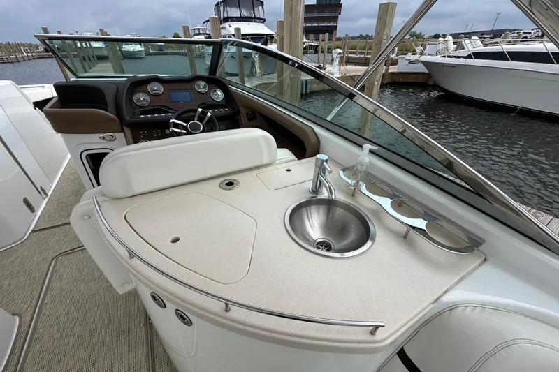Slide: The Image of 2015 Cobalt 336 boat interior with helm, sink, and seating at marina. - 12