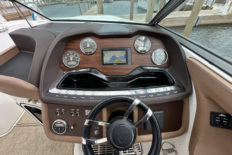 Slide: The Image of 2015 Cobalt 336 boat dashboard with gauges, GPS, and steering wheel at marina. - 15