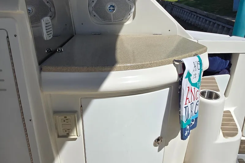 Slide: The Image of 2003 Regal Commodore 4260 boat interior with countertop, speakers, and decorative towel. - 24