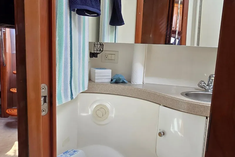 Slide: The Image of 2003 Regal Commodore 4260 yacht bathroom with sink, mirror, and striped towel. - 37