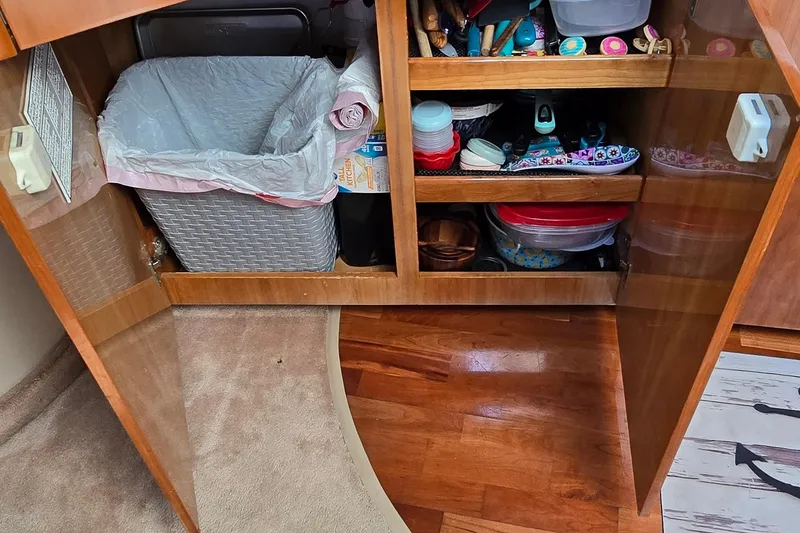 Slide: The Image of Open cabinet in 2003 Regal Commodore 4260, showing organized storage and trash bin. - 51