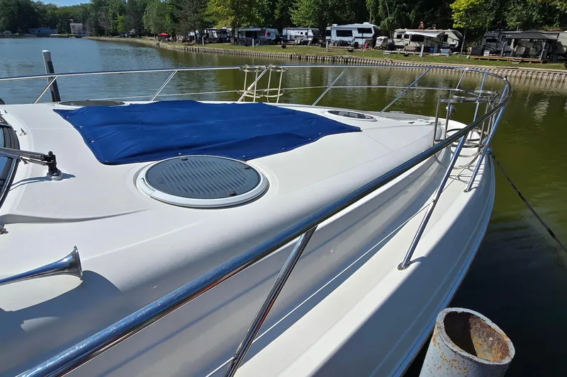 Slide: The Image of 2003 Regal Commodore 4260 yacht docked by a serene lakeside with lush greenery. - 9
