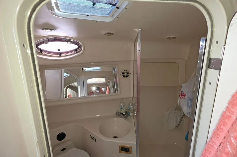 Slide: The Image of 1998 Sea Ray 370 Sundancer bathroom with sink, mirror, and porthole window. - 27