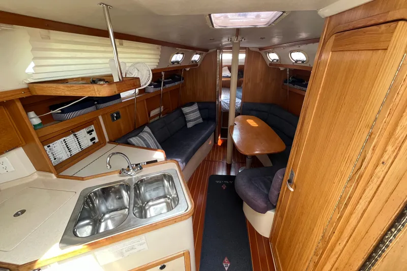 Slide: The Image of Interior of 2000 Catalina 320 sailboat with cozy seating and compact kitchen area. - 12