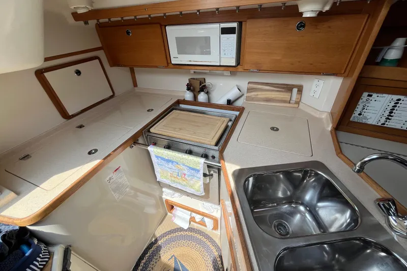 Slide: The Image of Compact kitchen in a 2000 Catalina 320 sailboat with stove, microwave, and sink. - 13
