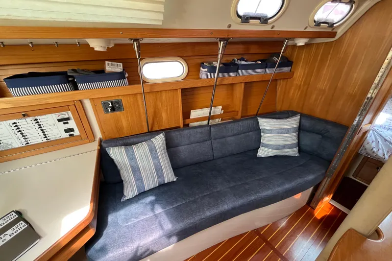 Slide: The Image of Interior of 2000 Catalina 320 sailboat with blue sofa, striped pillows, and wooden paneling. - 17