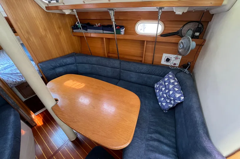 Slide: The Image of Cozy interior of 2000 Catalina 320 sailboat with wooden table and blue seating. - 20