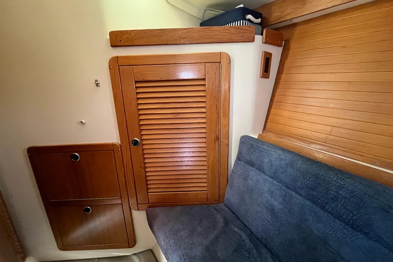 Slide: The Image of Interior of a 2000 Catalina 320 sailboat with wooden cabinetry and blue seating. - 23