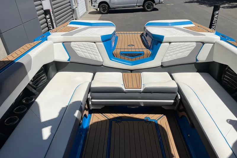 Slide: The Image of 2022 Nautique Super Air Nautique G25 interior with white and blue seating, teak flooring. - 10