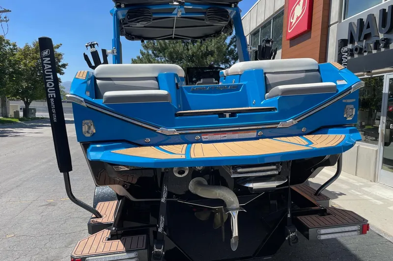 Slide: The Image of 2022 Nautique Super Air Nautique G25 boat, blue exterior, rear view, parked outdoors. - 5
