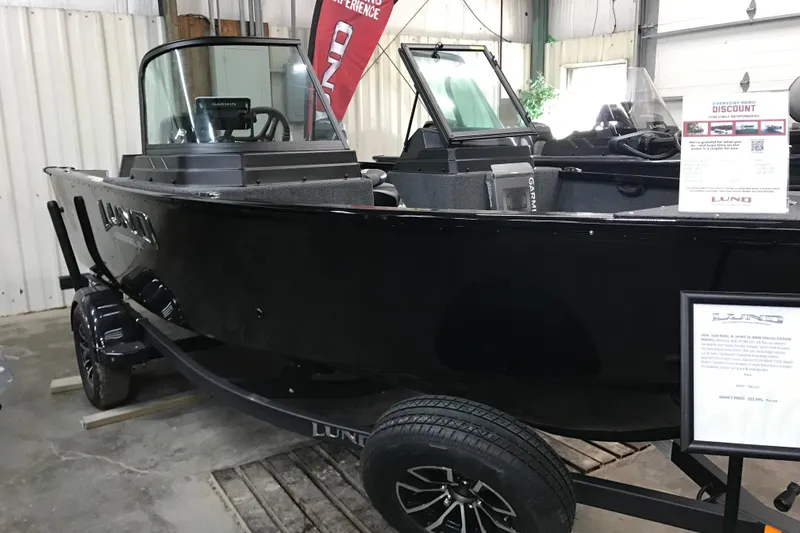 Slide: The Image of 2026 Lund 1650 Rebel XL Sport boat displayed indoors on a trailer. - 10