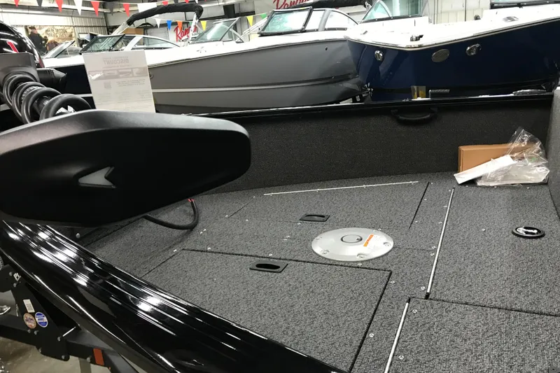 Slide: The Image of 2026 Lund 1650 Rebel XL Sport boat interior with storage compartments and motor. - 12