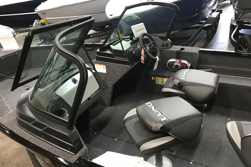 Slide: The Image of 2026 Lund 1650 Rebel XL Sport boat interior with steering console and branded seats. - 13