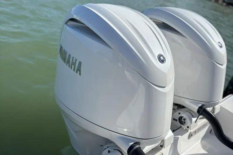 Slide: The Image of Twin Yamaha outboard engines on a 2024 Edgewater 262CC boat, docked on calm water. - 10
