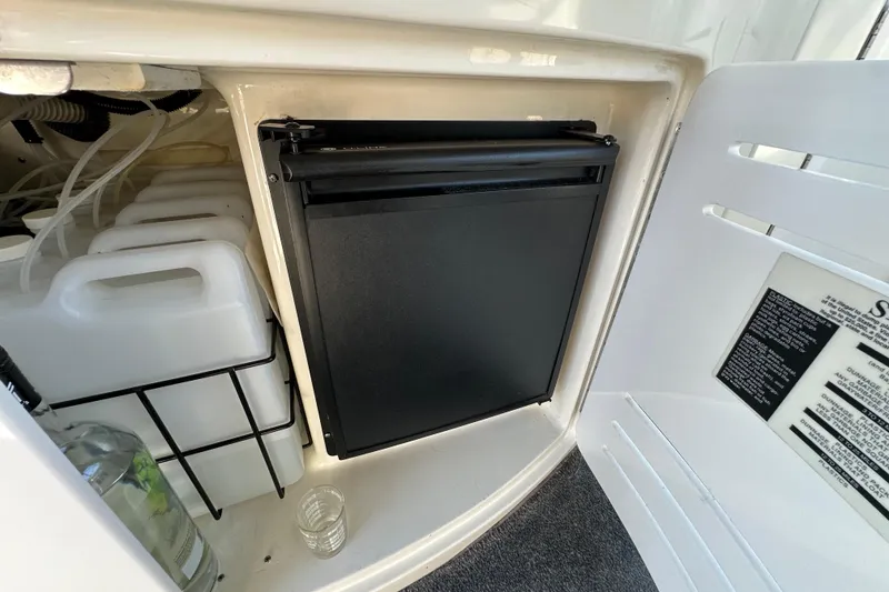 Slide: The Image of 2001 Sea Ray 510 Sundancer storage compartment with containers and a small refrigerator. - 8
