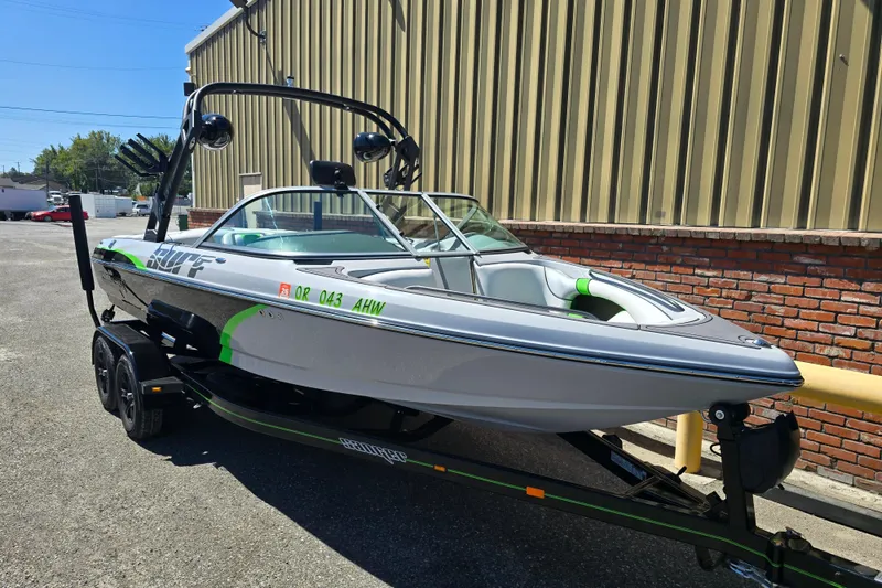 Slide: The Image of 2023 Sanger V215 boat on trailer, parked outdoors near a brick wall. - 17