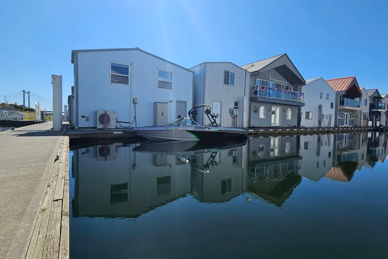 Slide: The Image of 2023 Sanger V215 boat docked by modern waterfront houses, reflecting on calm water. - 19