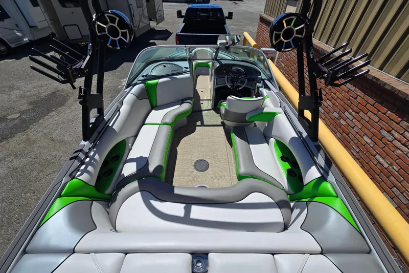 Slide: The Image of 2023 Sanger V215 boat interior with green and gray seating, speakers, and wakeboard racks. - 30