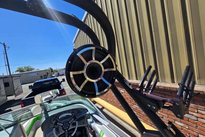 Slide: The Image of 2023 Sanger V215 boat with speaker and wakeboard rack, parked outdoors. - 35