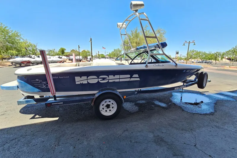 Slide: The Image of 2001 Moomba Outback boat on trailer, parked outdoors under clear blue sky. - 2