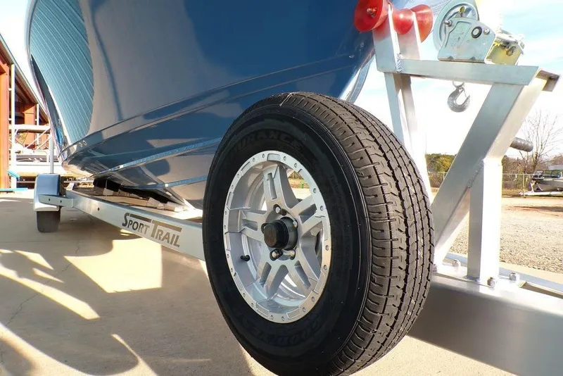 Slide: The Image of 2025 Sportsman Masters 247 boat on Sport Trail trailer, close-up of wheel and hull. - 13