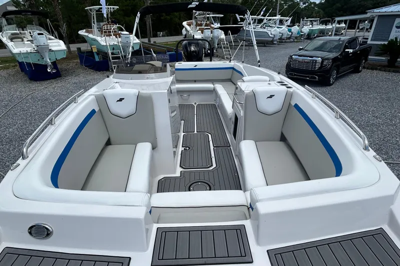 Slide: The Image of 2023 Starcraft SVX 231 OB DH boat interior with white and blue seating, docked outdoors. - 11