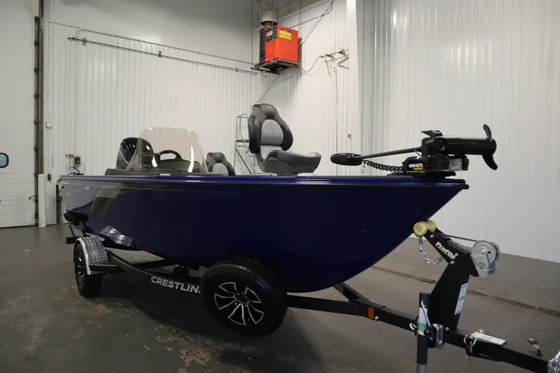 Slide: The Image of 2026 Crestliner 1650 Hawk Side Console boat in a showroom, on a trailer. - 2
