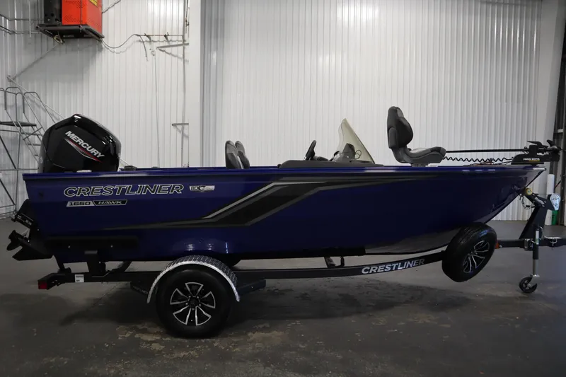 Slide: The Image of 2026 Crestliner 1650 Hawk Side Console boat in a showroom, featuring a Mercury engine. - 3