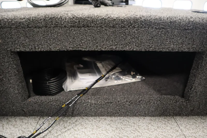 Slide: The Image of 2026 Crestliner 1750 Hawk Side Console storage compartment with coiled cable and accessories. - 14