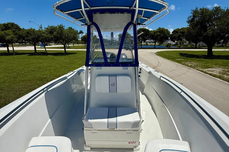 Slide: The Image of 2003 Sailfish 266 CC boat interior with seating and canopy, parked on a sunny day. - 10