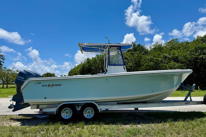 Slide: The Image of 2003 Sailfish 266 CC boat on trailer, parked outdoors under a clear blue sky. - 3
