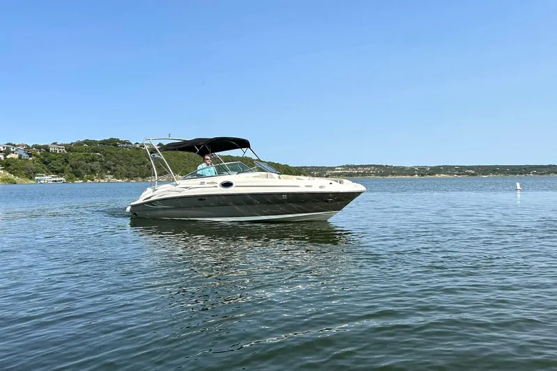 Slide: The Image of 2006 Sea Ray 240 Sundeck boat cruising on a scenic lake under clear blue skies. - 11