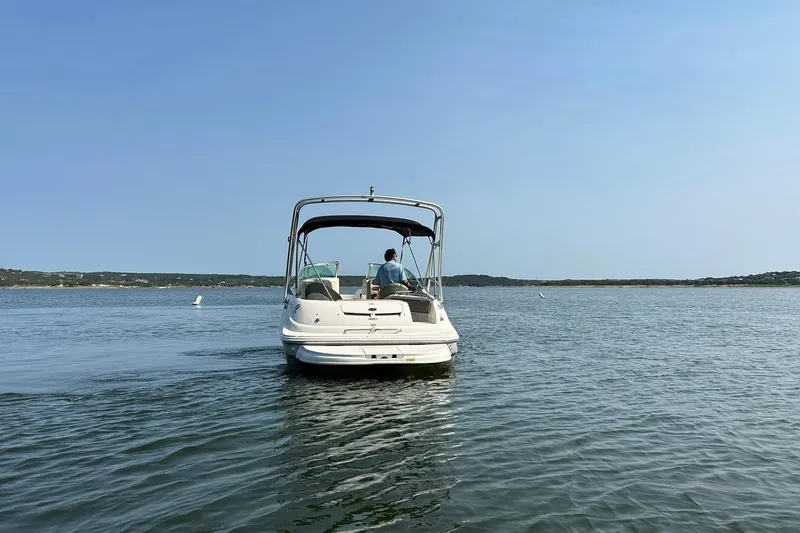 Slide: The Image of 2006 Sea Ray 240 Sundeck boat cruising on a calm lake under clear blue skies. - 16