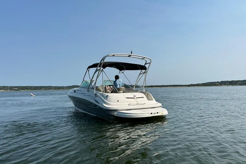 Slide: The Image of 2006 Sea Ray 240 Sundeck boat cruising on a calm lake under clear skies. - 17
