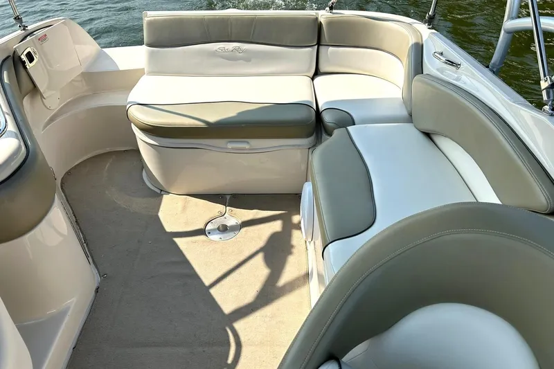 Slide: The Image of 2006 Sea Ray 240 Sundeck interior with beige and gray seating, on calm water. - 20