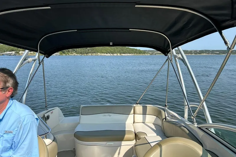 Slide: The Image of 2006 Sea Ray 240 Sundeck boat on a lake, featuring spacious seating and canopy. - 21