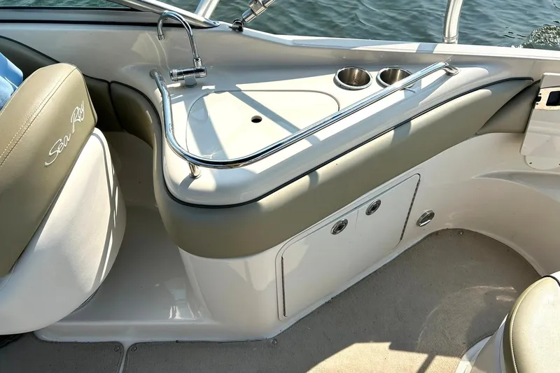 Slide: The Image of 2006 Sea Ray 240 Sundeck interior with sink and cup holders, featuring beige seating. - 25